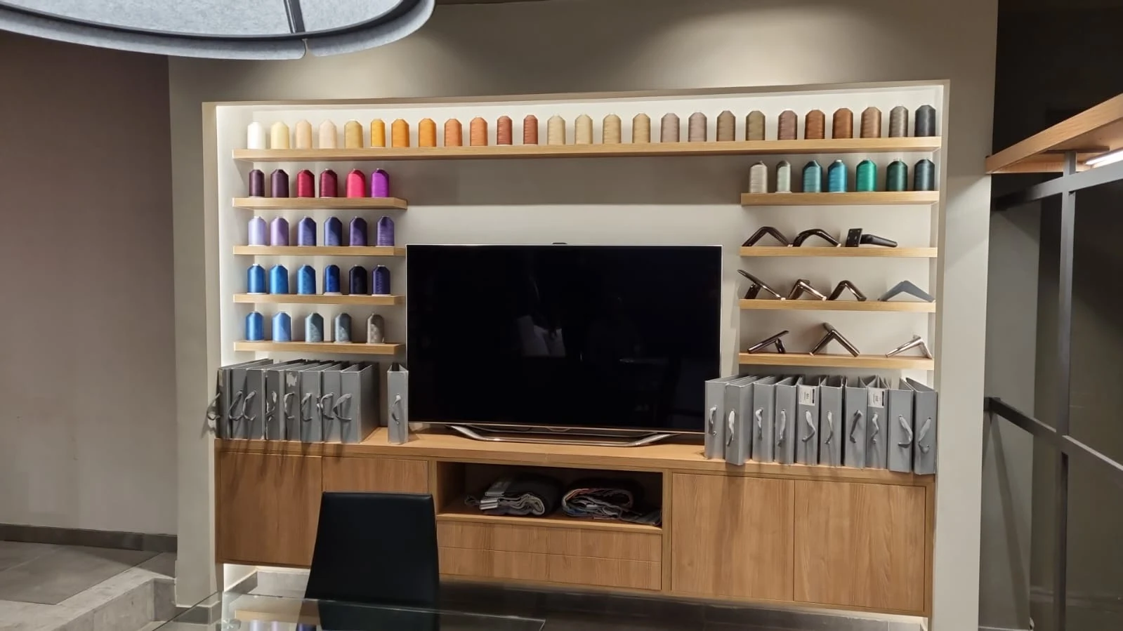 Muestrario del showroom renovado con telas organizadas por color, terminaciones y catálogos sobre un mueble de madera