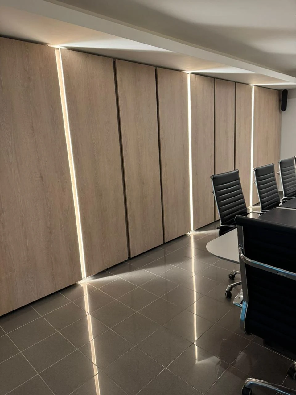 Paneles de tono madera con líneas verticales de luz en la sala de reuniones